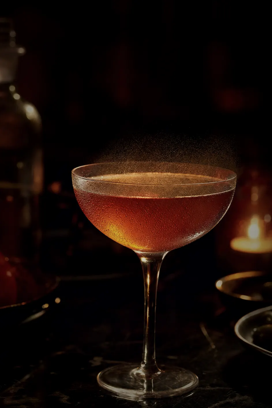 A backlit Argentine-inflected cocktail in a coupe glass with a fine citrus mist suspended above the surface.